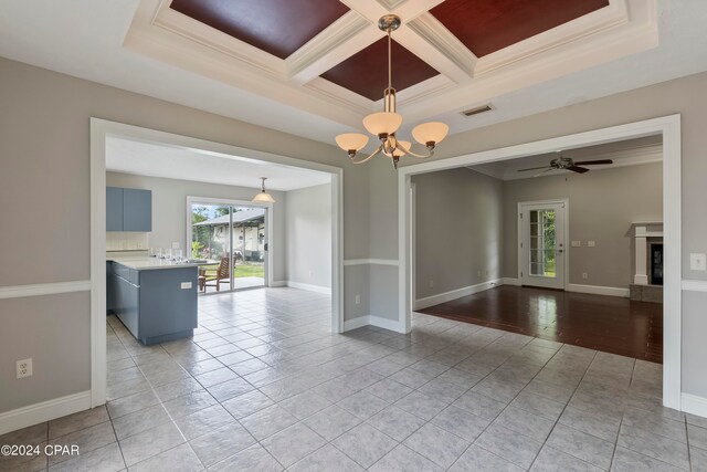 empty room with beamed ceiling, ceiling fan with notable chandelier, light tile floors, coffered ceiling, and ornamental molding