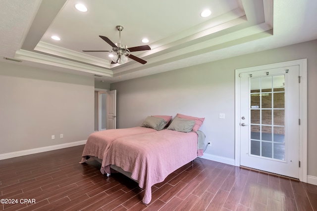 bedroom with dark hardwood / wood-style floors, ceiling fan, a raised ceiling, and access to outside