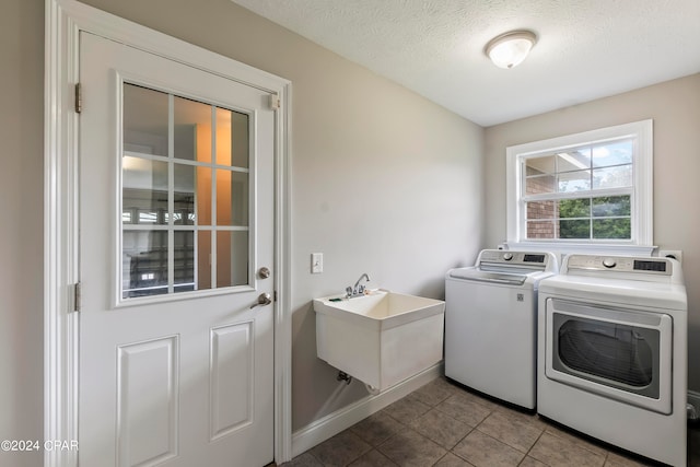 washroom with tile flooring, sink, a textured ceiling, and washing machine and dryer