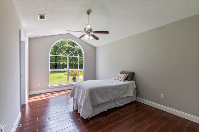 bedroom featuring dark wood-type flooring, ceiling fan, a textured ceiling, and lofted ceiling