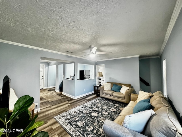 living area featuring a textured ceiling, wood finished floors, visible vents, baseboards, and crown molding