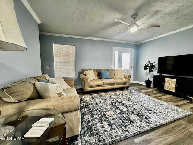 living room with baseboards, ceiling fan, wood finished floors, crown molding, and a textured ceiling