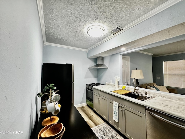 kitchen with crown molding, stainless steel appliances, gray cabinets, a sink, and wall chimney range hood