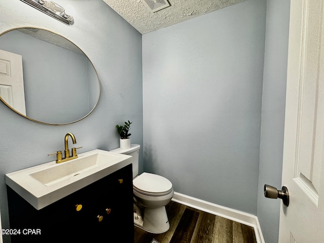 bathroom with vanity, a textured ceiling, wood-type flooring, and toilet