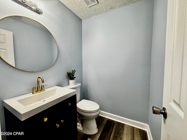 bathroom featuring visible vents, toilet, vanity, wood finished floors, and baseboards