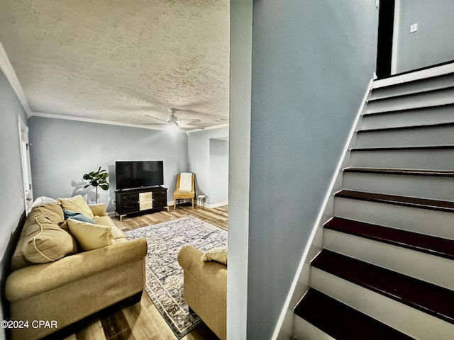 living area featuring crown molding, a textured ceiling, ceiling fan, and wood finished floors