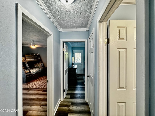 corridor featuring a textured ceiling, crown molding, and dark wood-type flooring