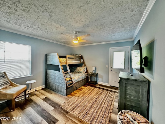 bedroom with baseboards, a textured ceiling, wood finished floors, and crown molding