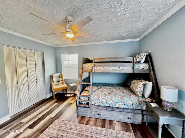 bedroom with ceiling fan, wood finished floors, baseboards, ornamental molding, and a closet