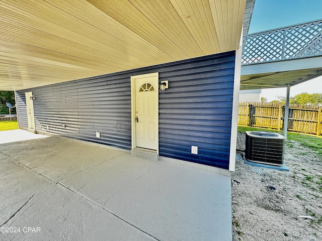 view of exterior entry featuring fence, central AC unit, and a patio