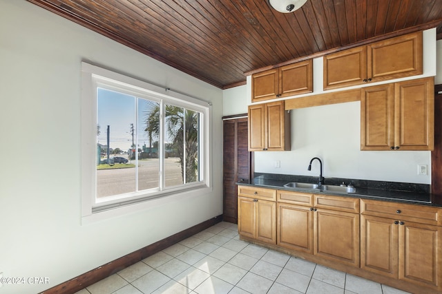 kitchen featuring sink, dark stone countertops, crown molding, light tile patterned flooring, and wood ceiling