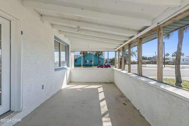 unfurnished sunroom featuring vaulted ceiling with beams