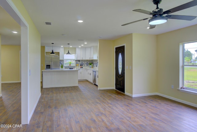 kitchen with white cabinets, backsplash, a kitchen island, pendant lighting, and appliances with stainless steel finishes