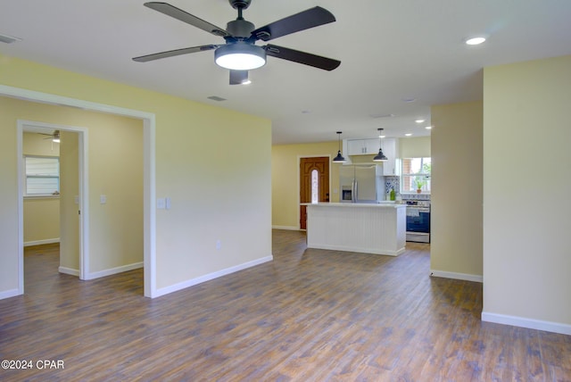 unfurnished living room featuring ceiling fan and dark wood-type flooring