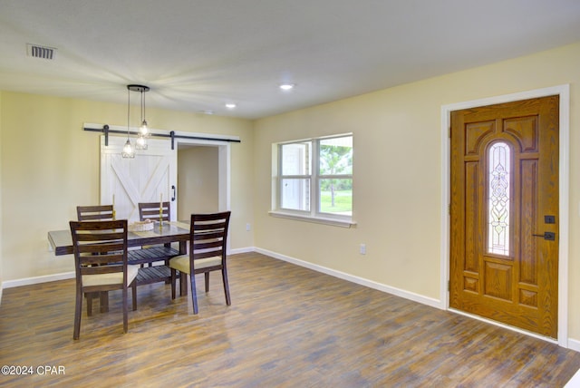 dining space with a barn door and dark hardwood / wood-style floors