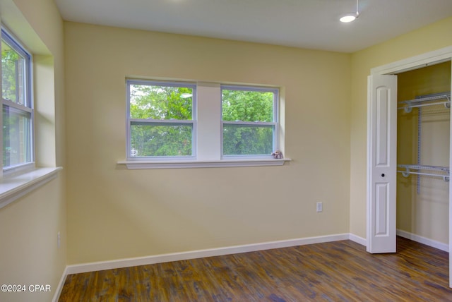 unfurnished bedroom with dark wood-type flooring, a closet, and multiple windows