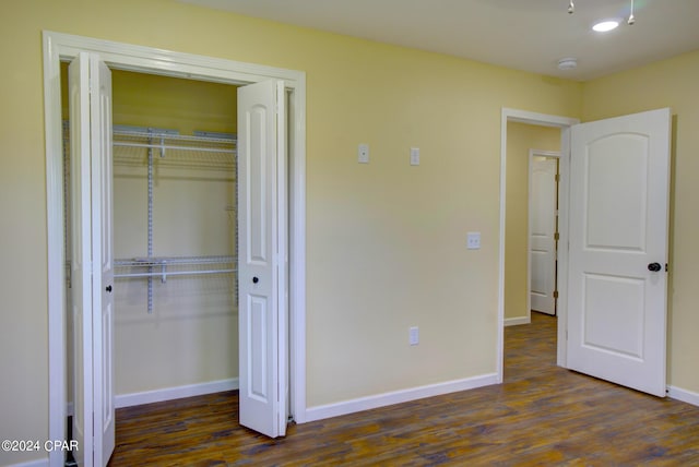 unfurnished bedroom with dark wood-type flooring and a closet