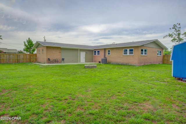 rear view of house featuring a fire pit, a yard, central air condition unit, and a patio