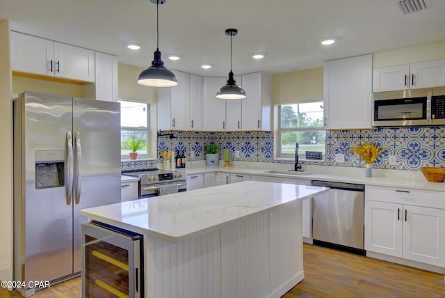 kitchen with sink, beverage cooler, appliances with stainless steel finishes, and white cabinetry