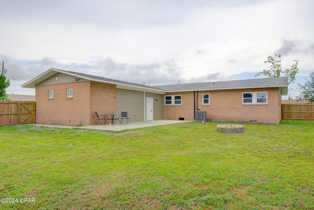 rear view of house with an outdoor fire pit, a patio, central AC, and a lawn