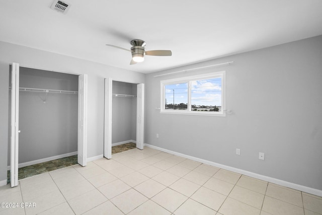 unfurnished bedroom featuring two closets, visible vents, and baseboards