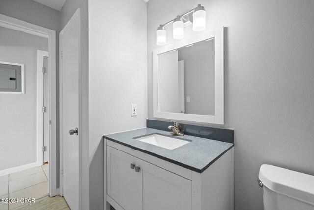 bathroom with electric panel, vanity, toilet, and tile patterned floors