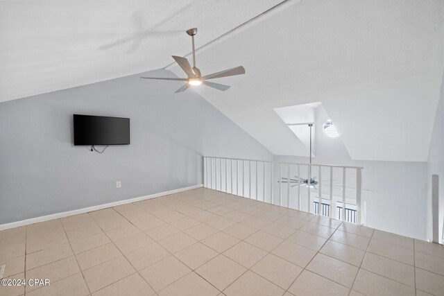 additional living space with ceiling fan, light tile patterned floors, and vaulted ceiling