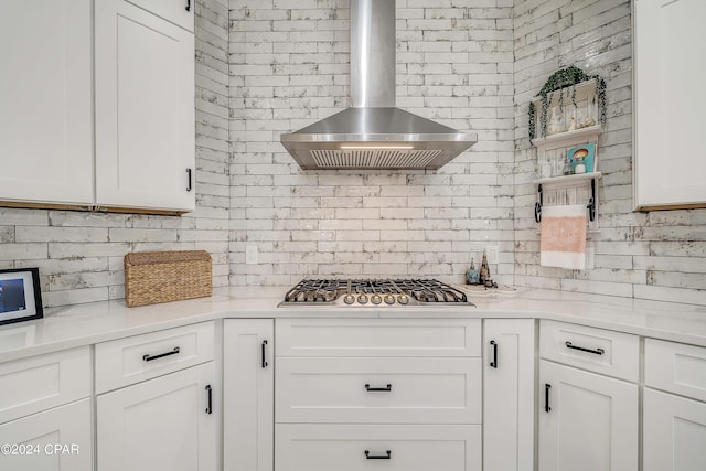 kitchen featuring open shelves, light countertops, stainless steel gas stovetop, white cabinetry, and wall chimney exhaust hood