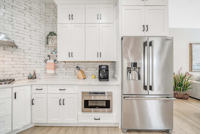 kitchen with white cabinets, light wood-style flooring, appliances with stainless steel finishes, open shelves, and backsplash