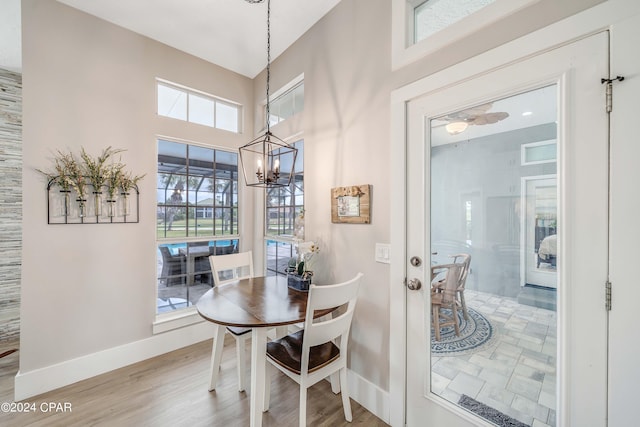 dining space featuring baseboards, a chandelier, and wood finished floors