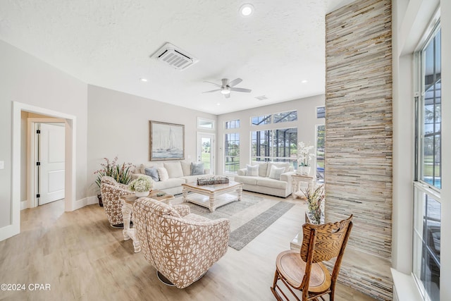 living area with a textured ceiling, ceiling fan, visible vents, baseboards, and light wood-style floors