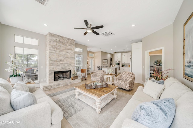 living room featuring visible vents, a tiled fireplace, ceiling fan, light wood-style floors, and recessed lighting