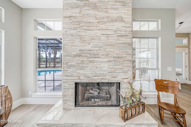 living area featuring a large fireplace, wood finished floors, and baseboards