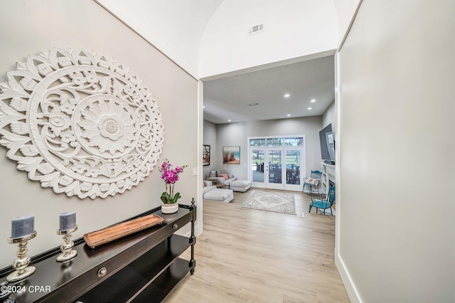 hall featuring recessed lighting, visible vents, a towering ceiling, wood finished floors, and baseboards