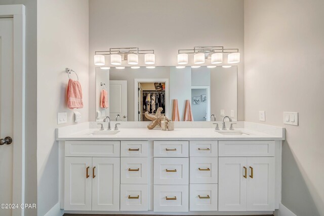 full bath with a sink, a spacious closet, and double vanity