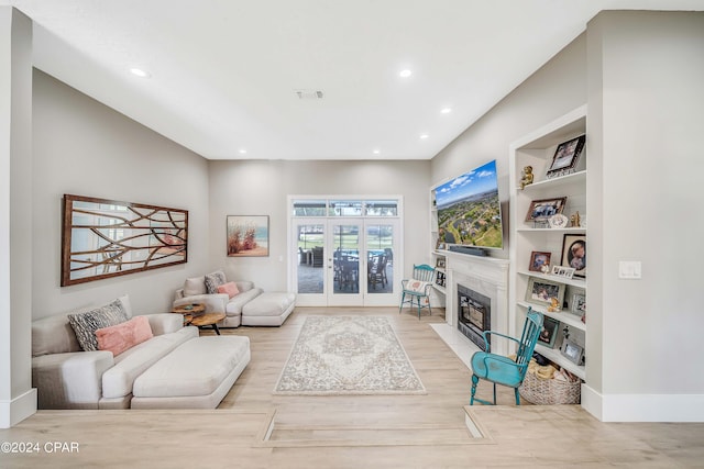 living area featuring built in shelves, recessed lighting, a premium fireplace, wood finished floors, and visible vents