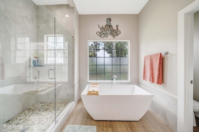 bathroom featuring a freestanding bath, a stall shower, wood finished floors, and toilet