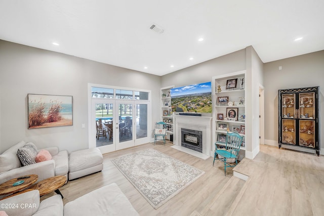 living area featuring light wood-style floors, a fireplace with flush hearth, visible vents, and recessed lighting