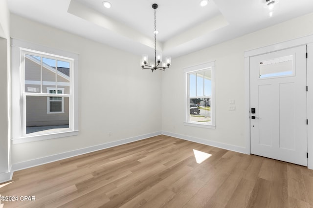 entrance foyer with a chandelier, light hardwood / wood-style floors, and a raised ceiling