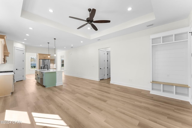 unfurnished living room featuring light wood-type flooring and a tray ceiling