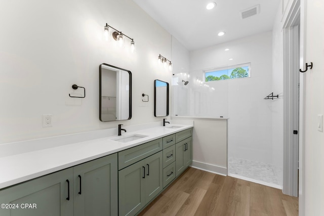 bathroom featuring a tile shower, vanity, and wood-type flooring