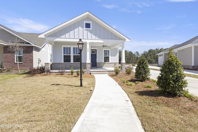 view of front of property with ceiling fan, covered porch, a front lawn, board and batten siding, and brick siding