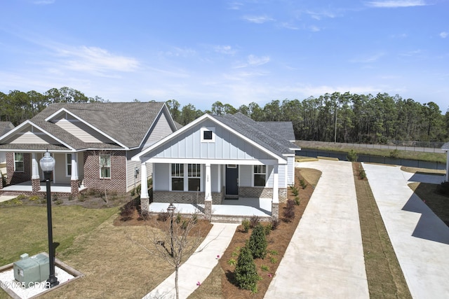 view of front of property with covered porch, a front lawn, board and batten siding, and brick siding