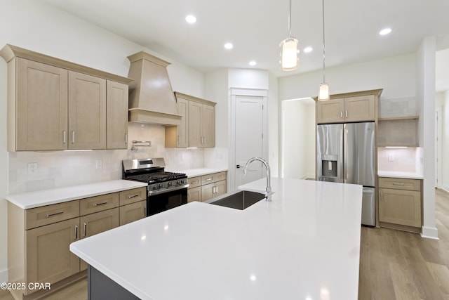 kitchen with stainless steel appliances, light wood-style floors, custom range hood, and a sink