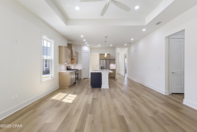 unfurnished living room featuring light wood-type flooring, visible vents, a tray ceiling, and baseboards