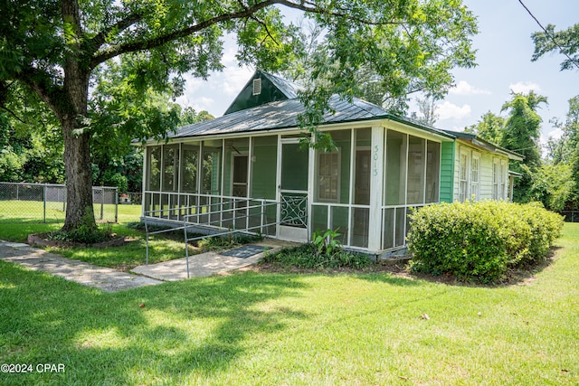 exterior space with a sunroom and a lawn