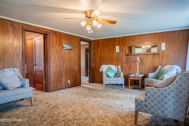 living area with carpet, ceiling fan, wooden walls, and crown molding