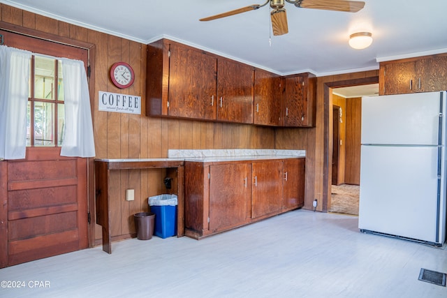 kitchen with white refrigerator, ceiling fan, wooden walls, and crown molding