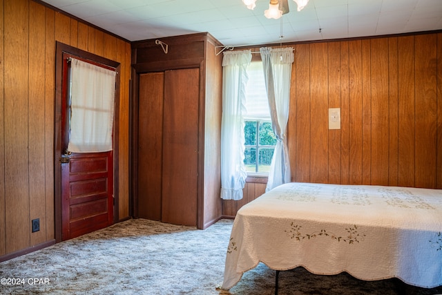 carpeted bedroom featuring wooden walls