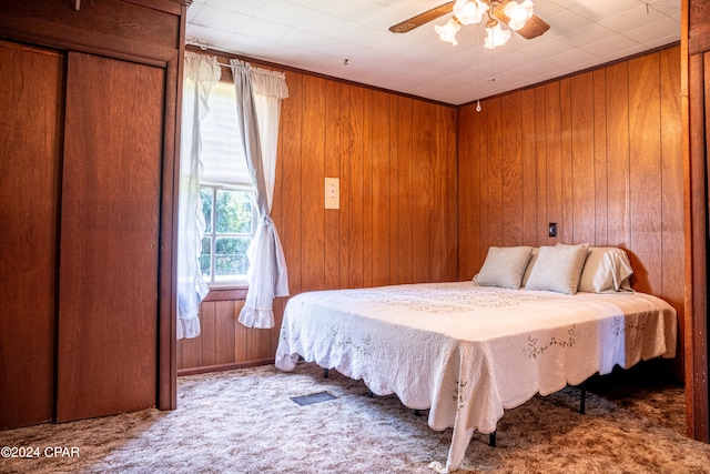 bedroom featuring wood walls, carpet, and ceiling fan